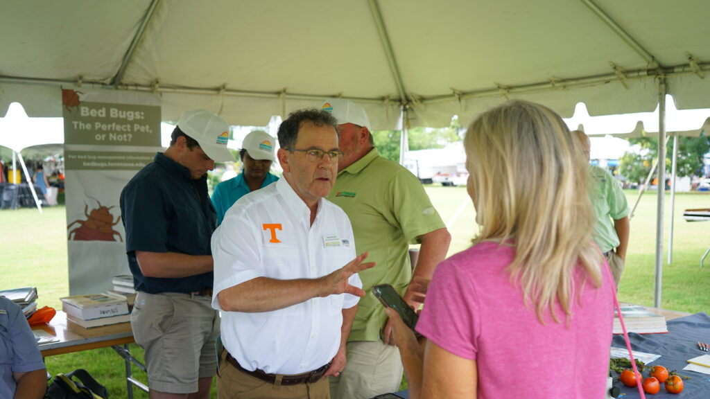 A man in a white shirt speaks with a woman at a plant diagnostic tent